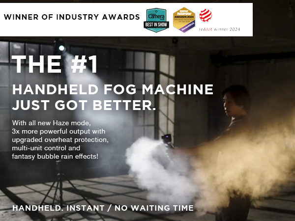 A person uses the SmokeNINJA Pro Trident Kit by PMI to emit white fog in an industrial setting, showcasing the #1 handheld fog machine known for its awards, upgraded features, and cinematic smoke effects.