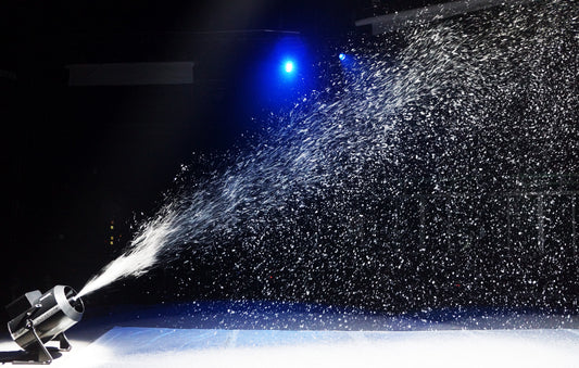 A DJ Power DJ Power H-SIP7 SNOWSTORM stage machine spraying a continuous stream of artificial snow with large snow output across a dark room.