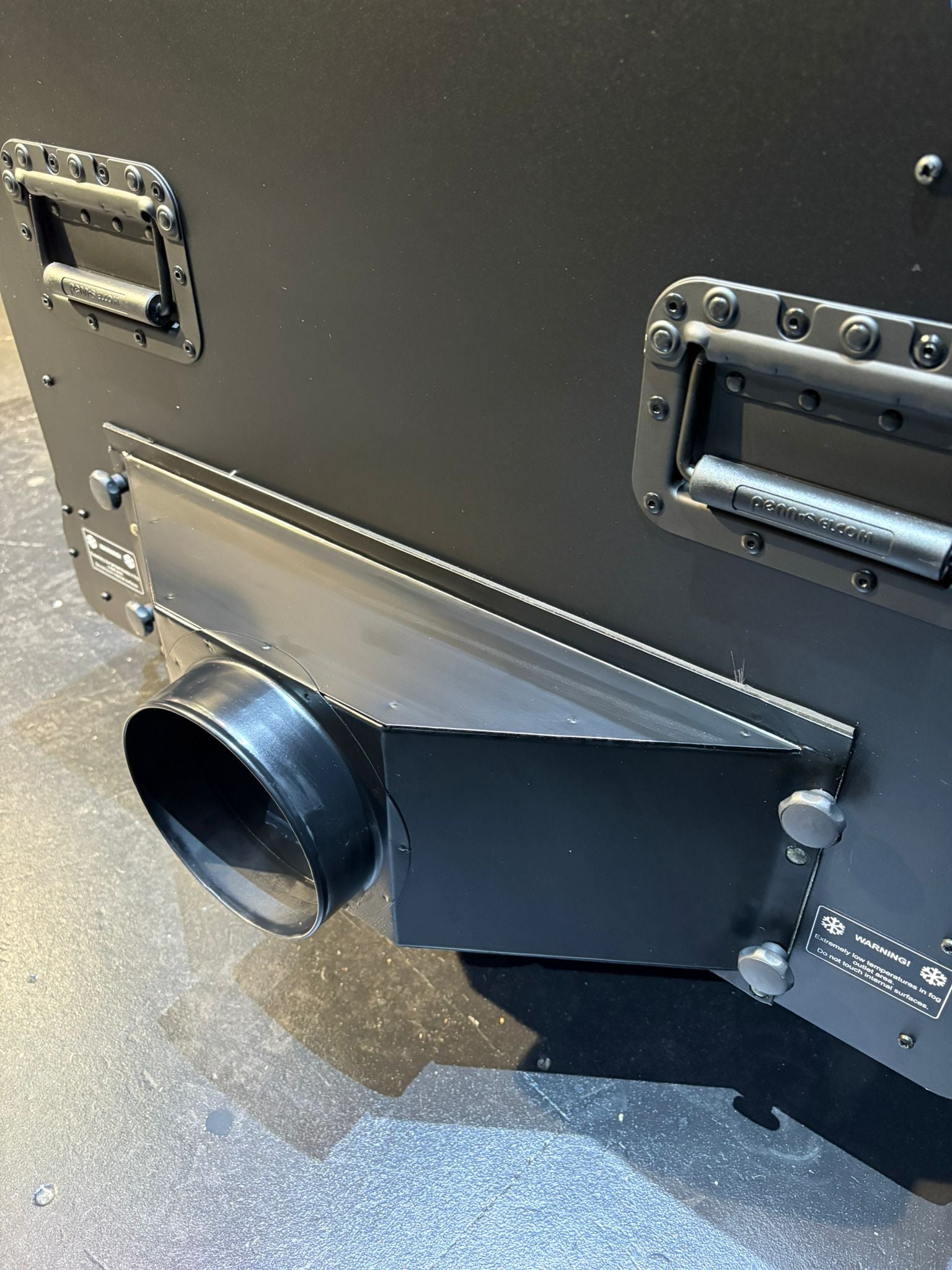 Metallic cylindrical object with a black exhaust or vent on a gray surface