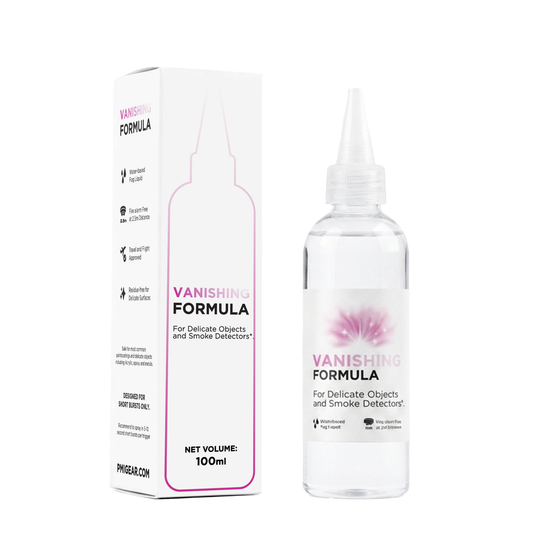 A clear plastic bottle of PMI SmokeNINJA PRO Vanishing Formula (100ml) with a pointed nozzle stands beside its white box. Both feature pink and black text, highlighting Residue Free Fog for delicate items and Smoke Detector Free usage.
