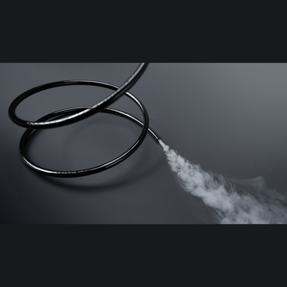 The PMI SmokeNINJA Special Effect Tubing Kit (PMI_AC_SMCKT) features black metal spiral tubing on a dark surface, emitting white smoke or vapor from its end and creating a dramatic contrast with the shiny metal.