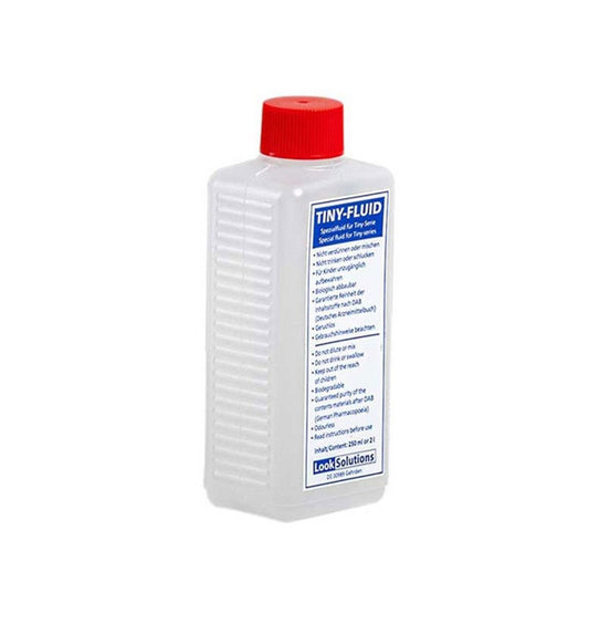 A clear 250ml rectangular plastic bottle labeled "Tiny Fog Fluid 250ml - Look Solutions," with a red screw cap, contains transparent fog fluid for dense effects; instructions and warnings are provided in German and English.