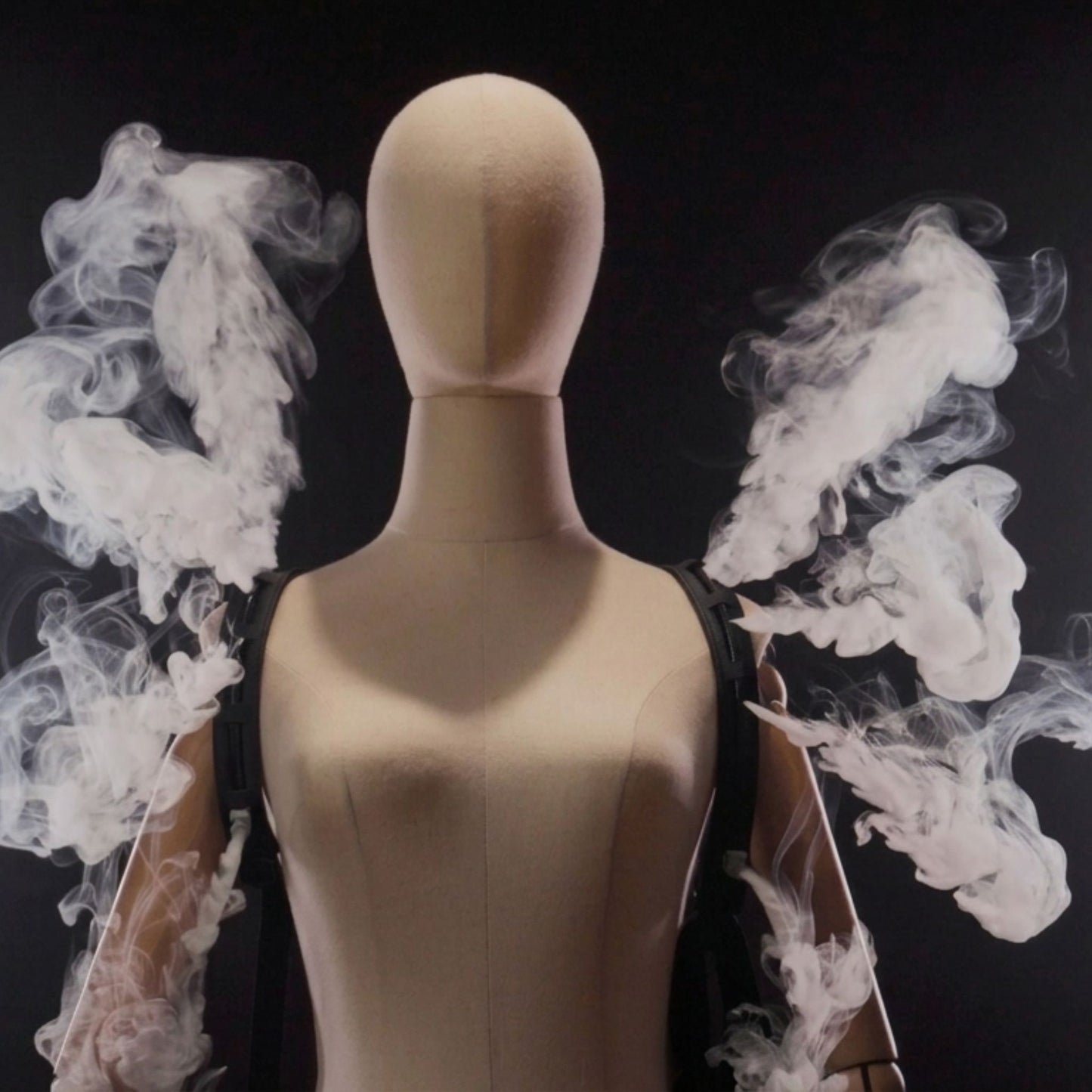 A featureless mannequin wears a PMI SmokeNINJA PRO/NINJA/GENIE PMI Smoke Vest (PMI_AC_SVEST) harness, emitting streams of white smoke from its shoulders that form wing-like shapes against a dark background.