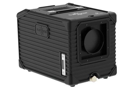 A black, rugged, cube-shaped electronic device with ribbed sides, a circular opening on one face, and labeled DJ Power. Designed as the DJ Power MINI AQUA LOW FOG MACHINE, it features various ports, buttons, and a handle on top for portability.