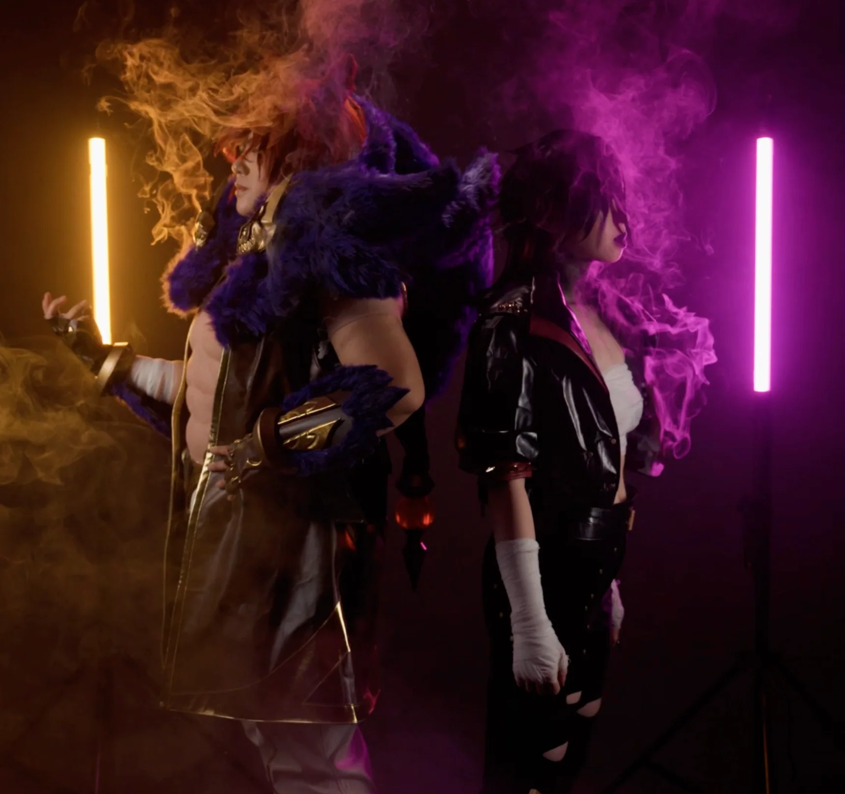 Two cosplayers stand back to back amid vibrant fog created by the PMI SmokeNINJA PRO/NINJA/GENIE PMI Smoke Vest, one in a furry armored costume, the other in a leather jacket, with vertical orange and pink lights illuminating the dramatic scene.