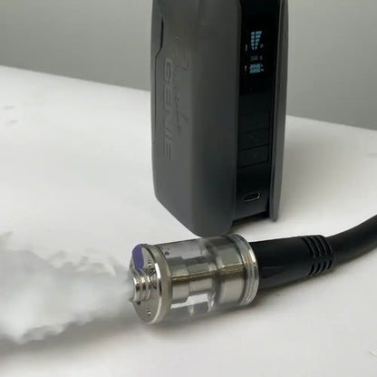A close-up of the PMI SmokeNINJA Extension Cable connected to a vaporizer, showing the mouthpiece and cable in focus as white vapor emits from the fog chamber, with device settings visible in the background.