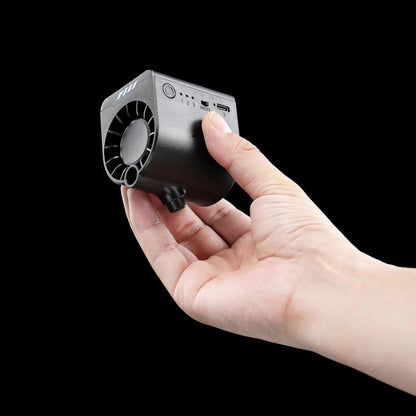 A hand holds the PMI SmokeNINJA Bluetooth Haze Fan 2.0—a compact black device with a vent, buttons, ports, and a haze nozzle designed for long-hanging haze—shown against a plain black background.