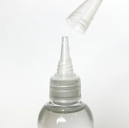 A close-up shows the PMI SmokeNINJA/GENIE Smoke Refill 100ml bottle with its transparent cap being lifted off the pointed nozzle, all set against a plain white background.