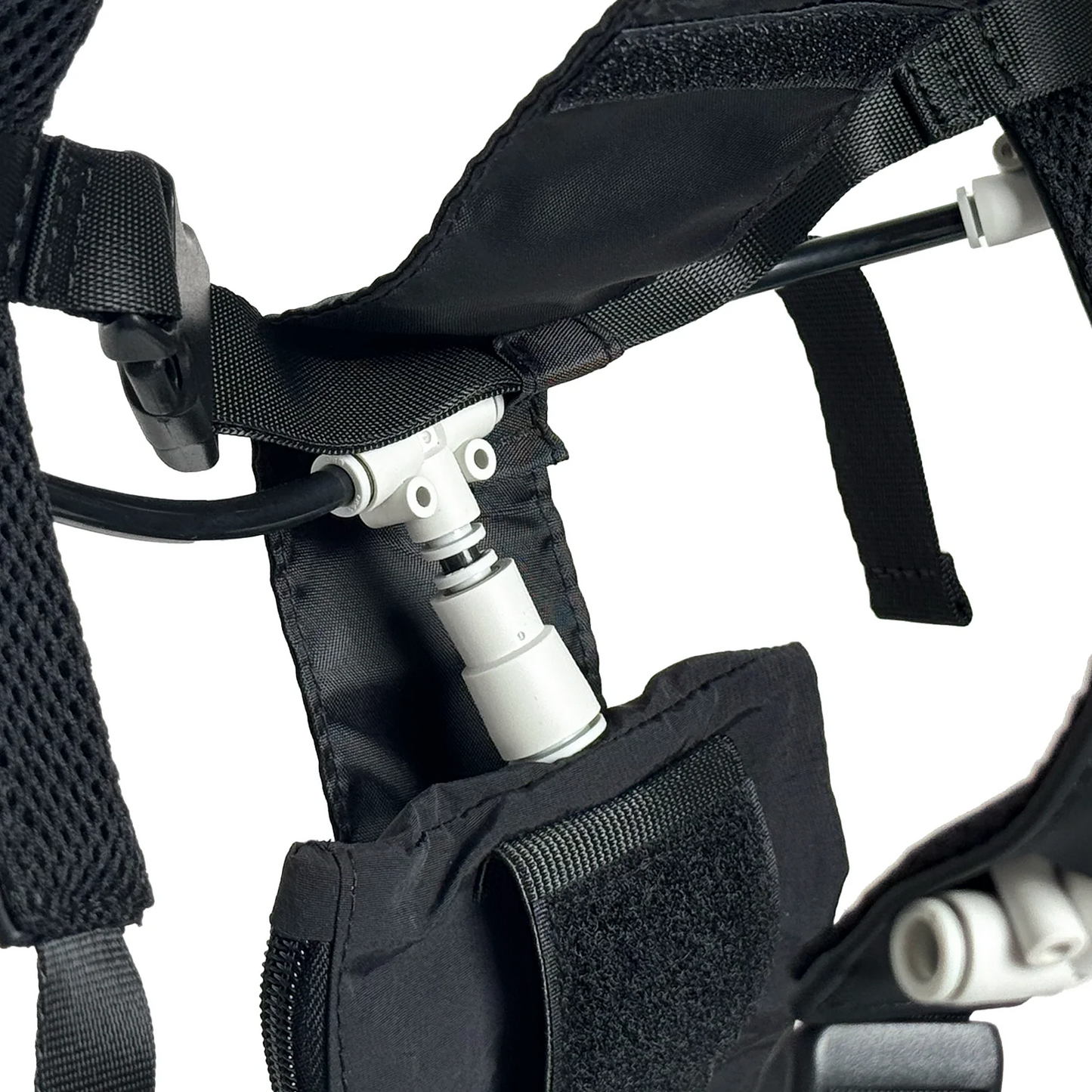Close-up of the PMI SmokeNINJA PRO/NINJA/GENIE Smoke Vest showing mesh straps, padded section, and a white plastic connector for an on-body smoke system, attached to a flexible tube and partly tucked in a Velcro-flap pocket.