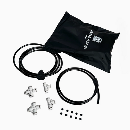 A black bag labeled PMI, two black tubes, four white plastic T-connectors, and eight small black circles—components for the PMI SmokeNINJA PRO/NINJA/GENIE Smoke Vest—are arranged on a white background.